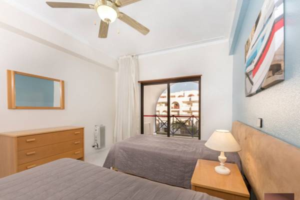 Schlafzimmer im Ukino Terrace Algarve mit zwei Betten, Nachttischen, Lampen und einem Fenster mit Balkon.