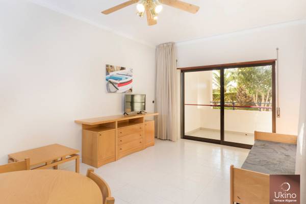 Innenraum des Ukino Terrace Algarve Hotels mit Wohnzimmer, Fernseher, Tisch und Stühlen.
