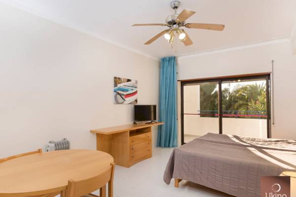 Innenansicht eines Zimmers im Ukino Terrace Algarve Hotel mit Bett, Tisch, Fernseher und Balkon.