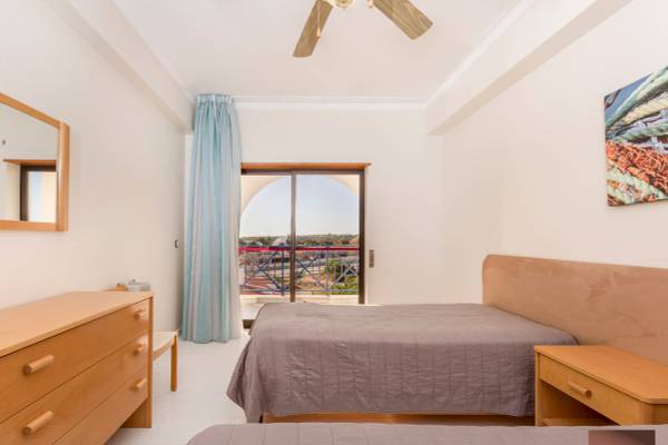 Schlafzimmer im Ukino Terrace Algarve Hotel mit zwei Betten, Kleiderschrank, Nachttisch und Balkonzugang.