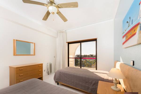 Schlafzimmer im Ukino Terrace Algarve Hotel mit zwei Betten, Nachttischen, Lampe, Spiegel und Klimaanlage.