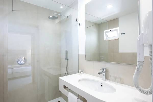 Badezimmer im Hotel Ancora Park mit glasdusche, spiegel und handtuchtrockner.