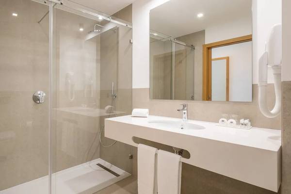Badezimmer im Ancora Park Hotel mit ebenerdiger Dusche, Waschbecken und Spiegel.