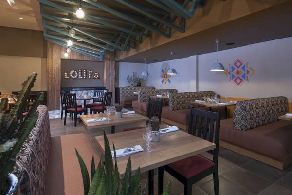 Innenansicht des Restaurants im Emotions By Hodelpa Hotel in Puerto Plata mit gepolsterten Sitzen und Tischen.