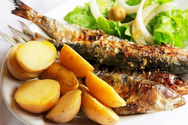 Ein Teller mit gegrilltem Fisch, Kartoffeln und Salat auf einem weißen Teller.
