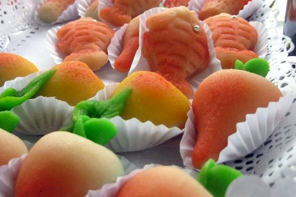 Nahaufnahme von verschiedenen fisch- und aprikosenförmigen kuchen in weißen papierförmchen