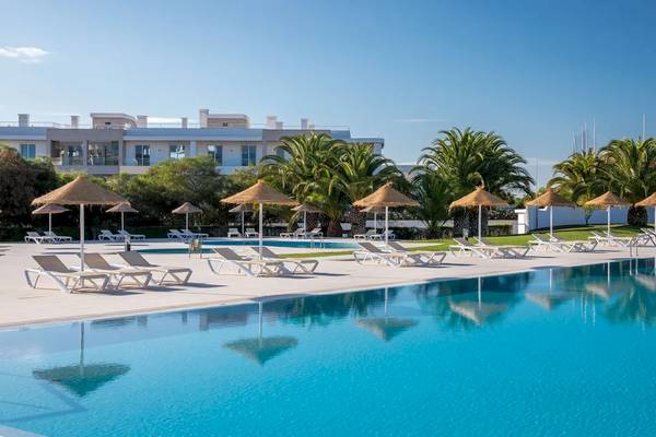 Strand mit Sonnenliegen und Sonnenschirmen vor einem Hotel im Ancora Park