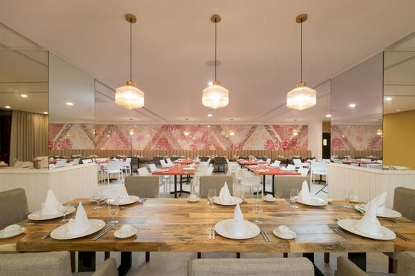 Innenansicht des Restaurants im Emotions By Hodelpa Hotel in Puerto Plata, mit gedeckten Tischen und stilvollen Wanddekorationen.