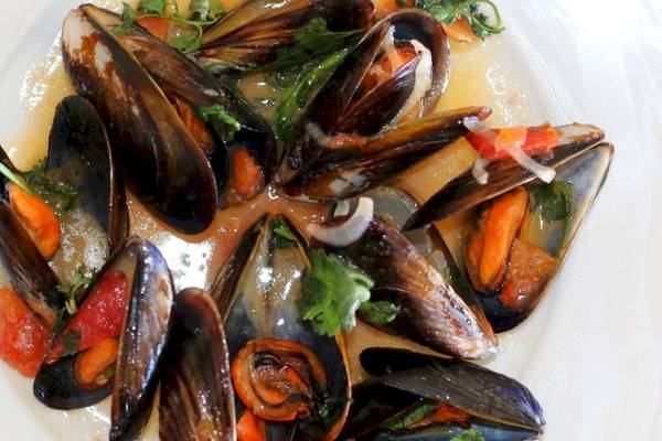 Nahaufnahme von gekochten Muscheln in einer Sauce auf einem weißen Teller.