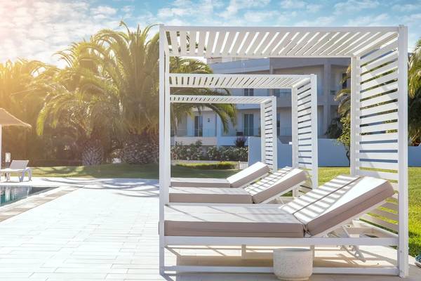 Pool-Loungebereich im Hotel Ancora Park mit weißen Sonnenliegen und Sonnenschirmen.