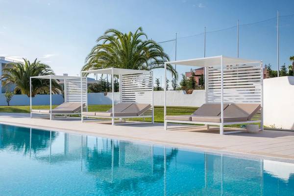 Drei weiße Sonnenliegen mit Überdachungen am Pool des Ancora Park Hotels.