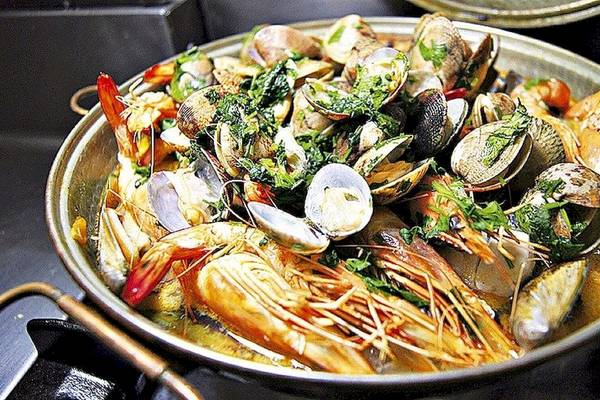 Muschelsuppe in einem Topf auf dem Herd, gefüllt mit Muscheln, Garnelen und Kräutern.