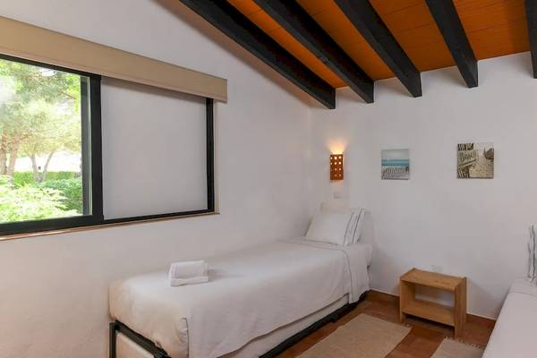 Schlafzimmer im Pedras da Rainha Resort mit zwei Einzelbetten, weißem Bettzeug, Nachttischen und dekorativen Wandleuchten.