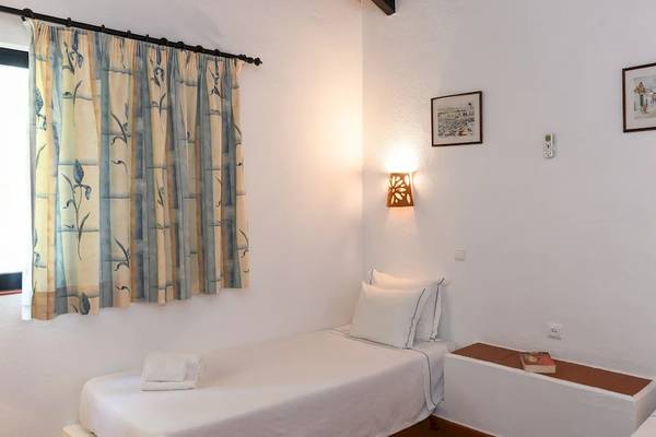 Ein Zimmer im Pedras da Rainha Resort mit zwei Betten, einem Fenster und einer Lampe an der Wand.