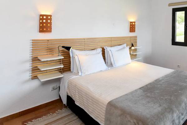 Ein Schlafzimmer im Pedras da Rainha Resort mit einem Bett, Nachttischen, Wandleuchten und einer Fensterbank.
