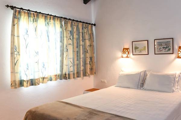 Ein Schlafzimmer im Pedras da Rainha Resort mit einem Bett, Kissen, zwei Lampen und einem Fenster.
