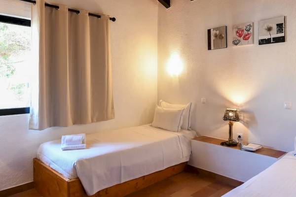 Zwei Betten in einem Zimmer im Pedras da Rainha Resort mit Nachttischen und Lampen.