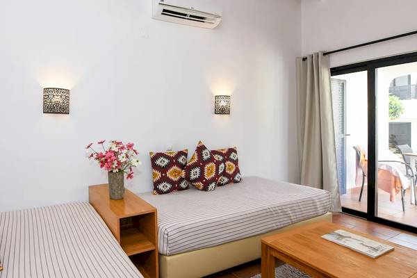 Ein modernes Hotelzimmer im Pedras da Rainha Resort mit zwei Betten, einem Tisch und einem Balkon.