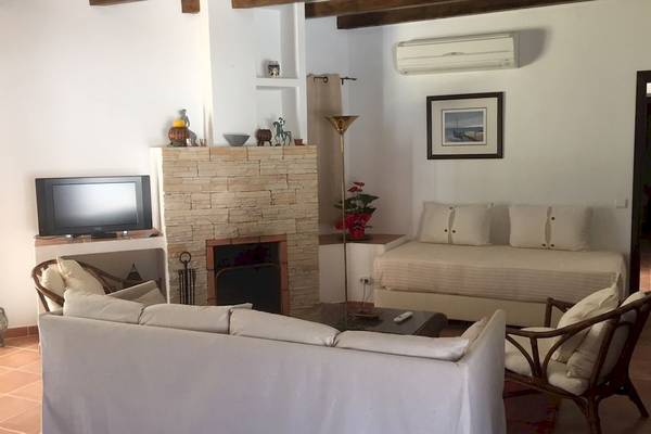 Wohnzimmer mit Sofa, Fernseher und Kamin im Pedras da Rainha Resort.