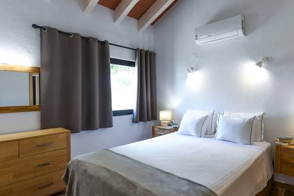 Schlafzimmer im Pedras da Rainha Resort mit weißem Bett, grauer Decke, Holzkommode und Spiegel