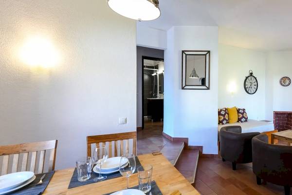 Inneneinrichtung des Pedras da Rainha Resorts mit Esstisch, Sesseln, Fernseher und Blumenvase.