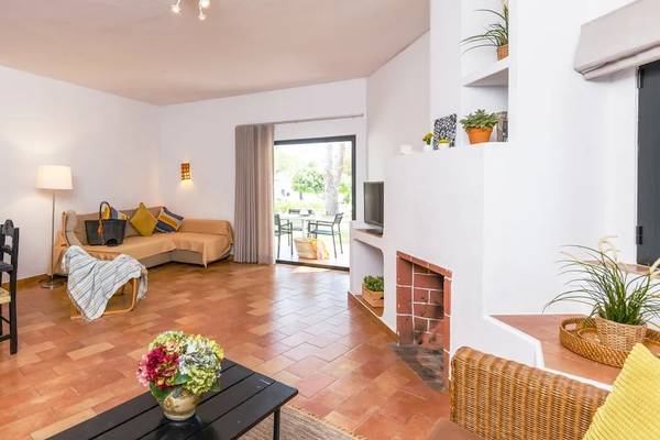 Wohnbereich des Pedras da Rainha Resorts mit Esstisch, Sofa und Fernseher.