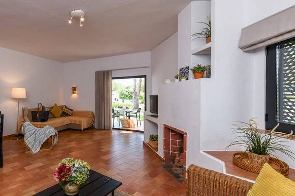 Wohnzimmer im Pedras da Rainha Resort mit Esstisch, Sofa und Kamin.