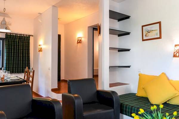 Wohnzimmer mit Sofa, Tisch und Fenstern im Pedras da Rainha Resort.