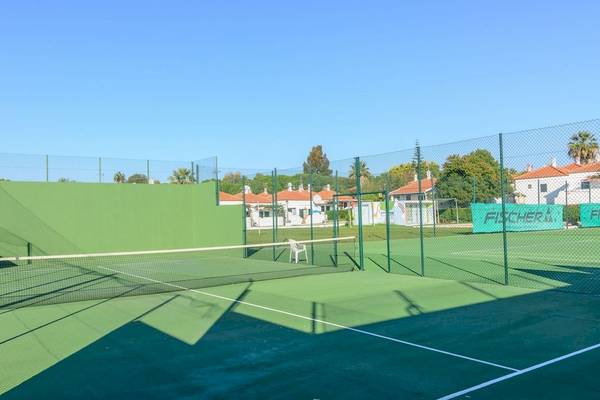 Tennisplatz im Pedras da Rainha Resort mit grünen Wänden und Schatten