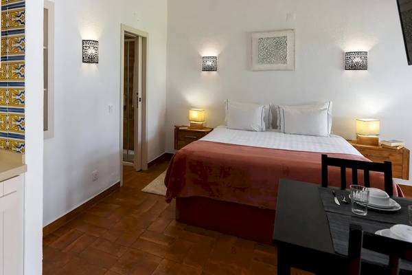 Ein modernes Zimmer im Pedras da Rainha Resort mit Kochnische, Bett und Tisch.