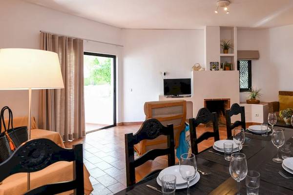 Speisezimmer im Pedras da Rainha Resort mit Tisch, Stühlen, Fernseher und Lampen.