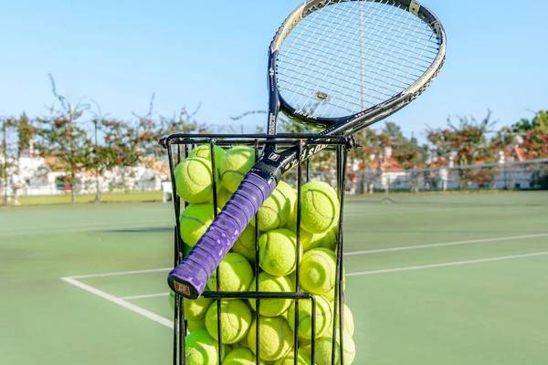 Korb voller Tennisbälle auf einem Tennisplatz im Freien