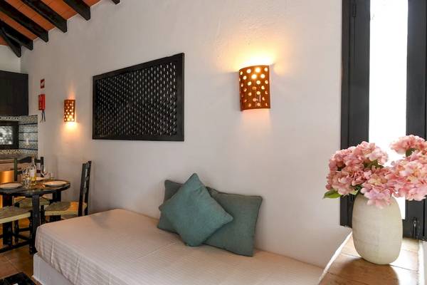 Kleines Schlafzimmer im Pedras da Rainha Resort mit Tisch, Stühlen, Kissen und Blumenvase