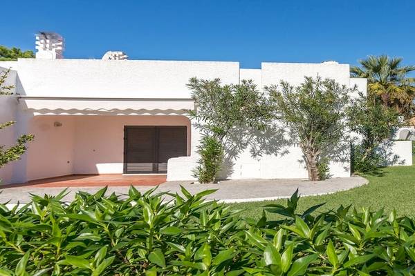 Außenansicht des Pedras da Rainha Resorts, ein weißes Gebäude mit gepflegtem Rasen und Bäumen.