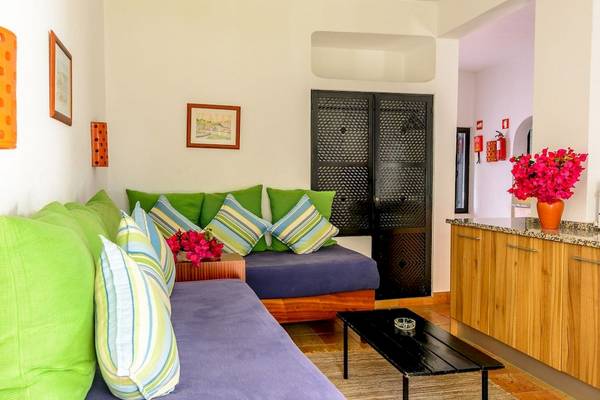 Innenbereich eines Hotels mit einem Sofa, bunten Kissen und einer grünen Pflanze.