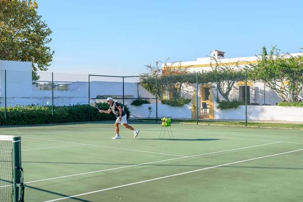 Tennisspieler im Pedras da Rainha Resort spielt mit einem Tennisschläger.