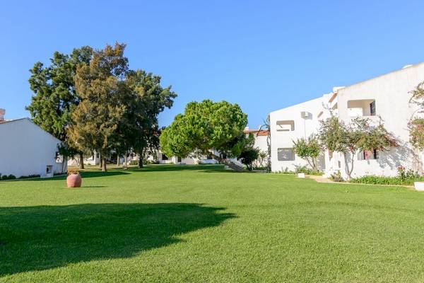 Außenbereich des Pedras da Rainha Resorts mit Rasen, Bäumen und Gebäuden