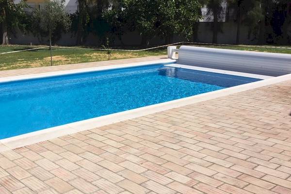 Ein blauer Swimmingpool mit einer weißen Umrandung im Freien vor dem Pedras da Rainha Resort.