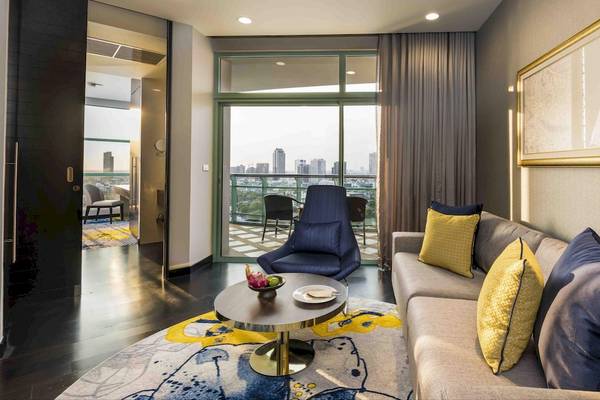 Das Wohnzimmer im Chatrium Hotel Riverside Bangkok mit einem Sofa, einem Tisch und einem Balkon mit Stadtblick.
