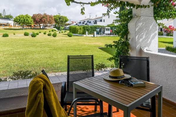 Aussicht von der Terrasse des Pedras da Rainha Resorts auf eine gepflegte Rasenfläche.