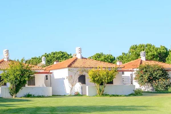 Außenansicht des Pedras da Rainha Resorts mit weißen Gebäuden und roten Dächern auf einem gepflegten Rasen