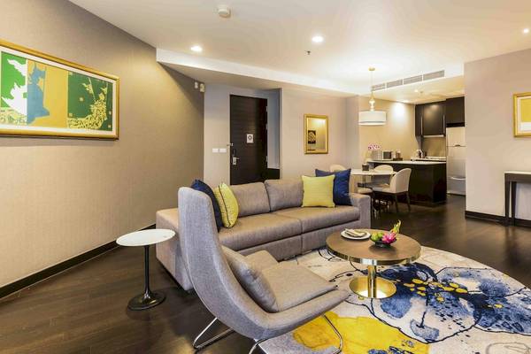 Wohnzimmer des Chatrium Hotel Riverside Bangkok mit Sofa, Tisch und Esstisch.