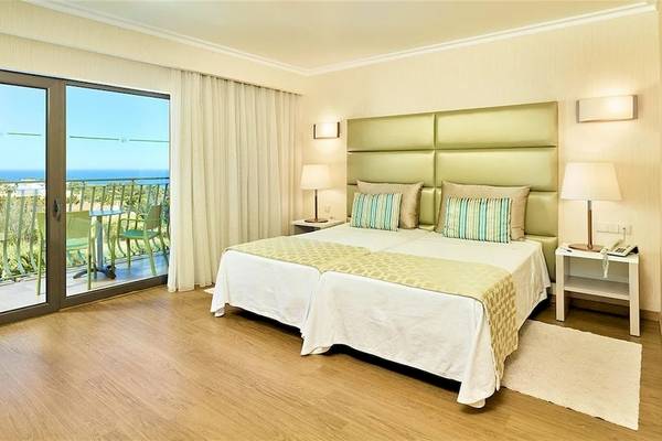 Doppelzimmer im Baia Grande Hotel mit Balkon und Meerblick, inklusive zweier Betten, Lampen und Gartenmöbeln.