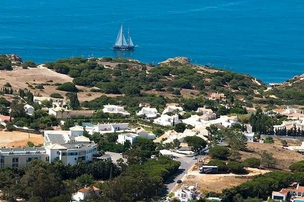 Luftaufnahme des Baia Grande Hotels am Meer mit einem Segelboot im Hintergrund.