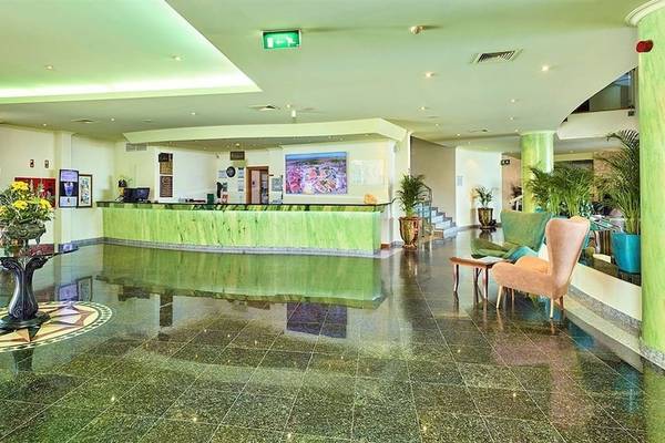 Empfangshalle des Baia Grande Hotels mit grüner Theke und üppiger Inneneinrichtung