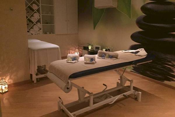 Massageraum im Baia Grande Hotel mit Behandlungstisch, Liegen und steinigen Dekoration.