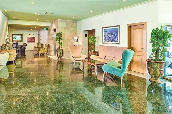 Lobby des Baia Grande Hotels mit grünen Fliesen, Möbeln und Pflanzen.