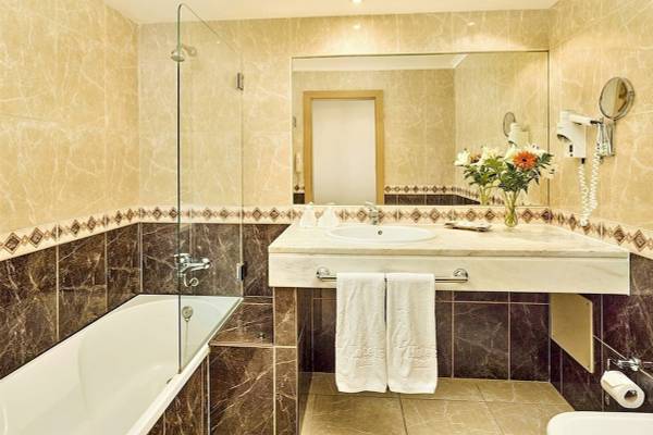 Badezimmer im Baia Grande Hotel mit Badewanne, Waschbecken und Spiegel.