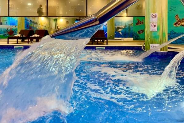 Wasserfall im Poolbereich des Baia Grande Hotels mit blauem Wasser und grünen Wandmalereien.