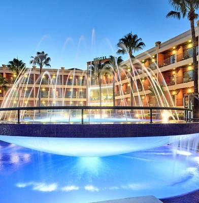 Der Außenpool des Baia Grande Hotels bei Nacht mit Wasserfontäne und Beleuchtung.